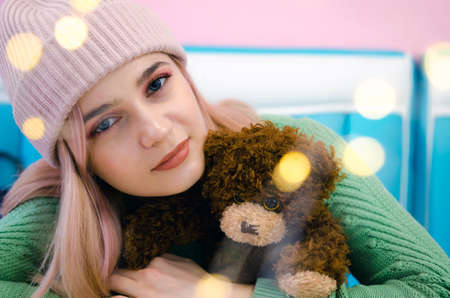 Portrait of a pretty girl in green sweater. Woman with Taddy Bear. Bokeh lights
