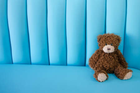 Sitting toy bear on the sofa. Blue backgroundの写真素材