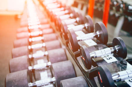Close up many dumbbells in sport fitness centre. Sport, fitness and motivation concept
