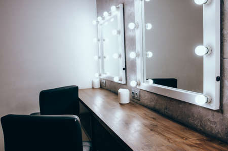 Interior of a beauty salon. Room with make up mirror lights and black chairの写真素材