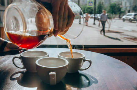 Barista pouring coffee from the into the ceramic white cup. Coffee shop terraceの写真素材