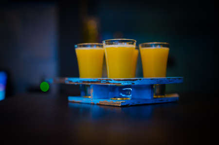 Set of yellow shots in one row, four servings on a wooden standの写真素材