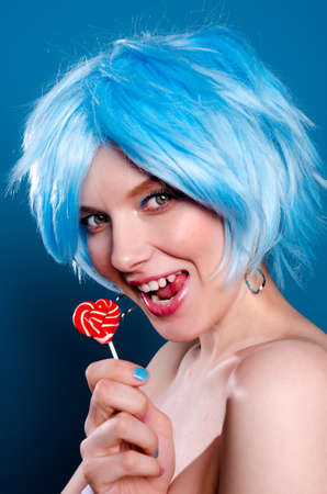 Cheerful glamorous woman  in blue wig with a lollipop in her handsの写真素材