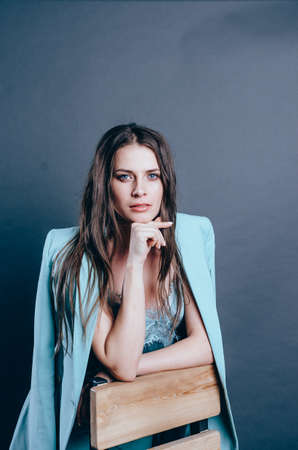 Young female business coach. Portrait of young woman in blue suit. Grey background in studio. Total...