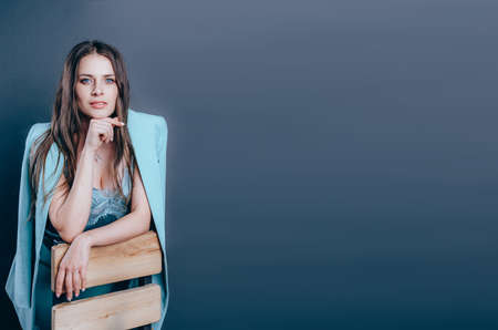 Young female business coach. Portrait of young woman in blue suit. Studio shot on grey