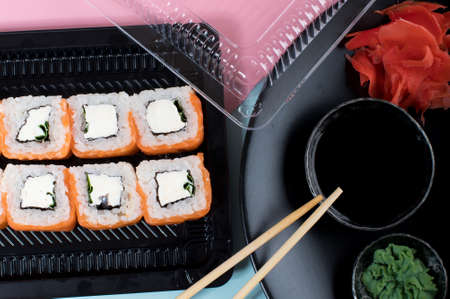 Sushi rolls set with red mayonnaise sauce and Philadelphia 
served on black plate. Pink and blue background. Top view. Flat layの写真素材