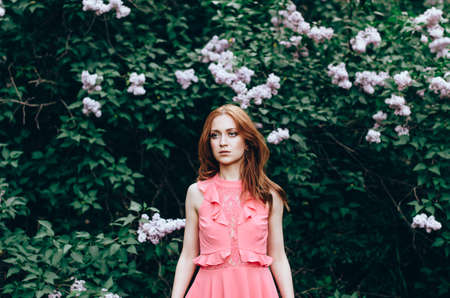 Young beautiful girl in a pink dress in the gardenの写真素材