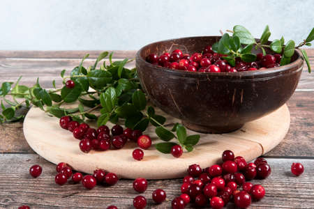 Ripe fresh cowberry in wooden bowl on rustic wooden table