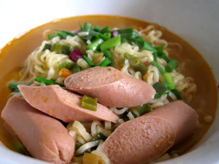 a bowl of instant noodles with spring onion and sausage の写真素材