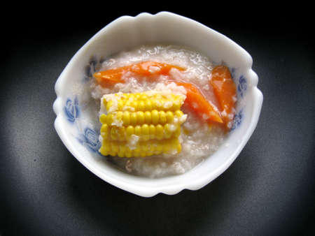 a bowl of porridge with corns and carrotの写真素材