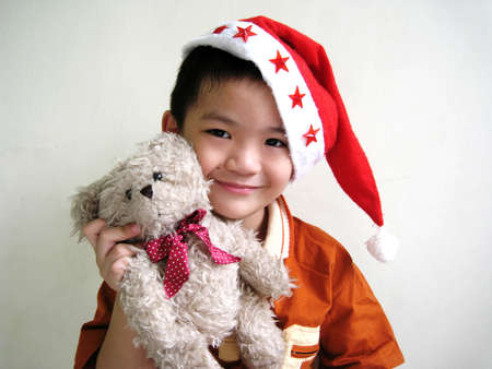 a asian boy wearing santa hat and holding a bearの写真素材