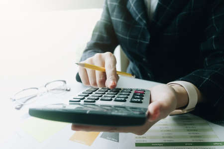 Close up Business woman using calculator for do math finance on wooden desk in office and business working background, tax, accounting, statistics and analytic research conceptの写真素材