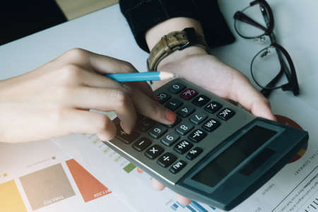 Close up Business woman using calculator for do math finance on wooden desk in office and business working background, tax, accounting, statistics and analytic research conceptの写真素材