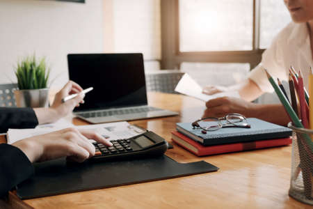Close up Businessman and partner using calculator and laptop for calaulating finance, tax, accounting, statistics and analytic research conceptの写真素材