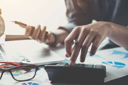Close up of businesswoman or accountant hand holding pen working on calculator to calculate business...