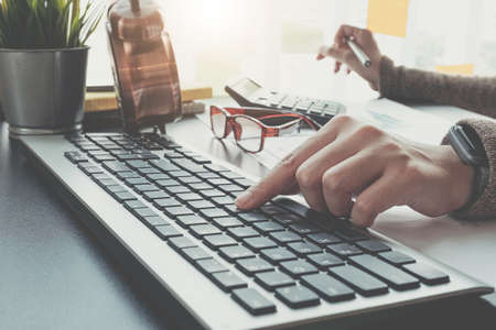 Close up of businesswoman or accountant hand holding pencil working on calculator to calculate...