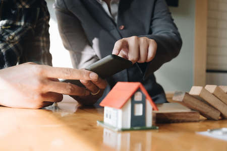 Close up of Businesswoman and customer pointing and using smartphone for buying house. Bank manager concept.の写真素材