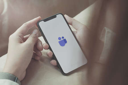 CHIANG MAI, THAILAND - APR 06 2020 :woman holding smartphone with Microsoft Teams communications platform logo. Teams is a unified team communication and collaboration platform with workplace chat, video meetings, and file storage.のeditorial素材
