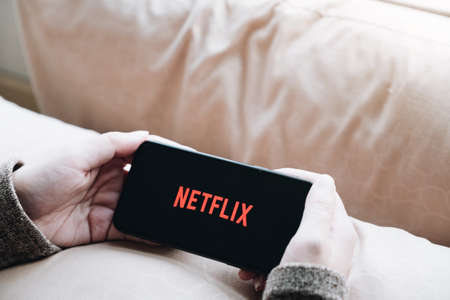 CHIANG MAI, THAILAND, APR 06 , 2020: Woman hand holding Smart Phone with Netflix logo on Apple iPhone Xs. Netflix is a global provider of streaming movies and TV series.のeditorial素材