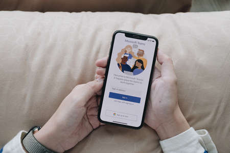 CHIANG MAI, THAILAND - APR 06 2020 :woman holding smartphone with Microsoft Teams communications platform logo. Teams is a unified team communication and collaboration platform with workplace chat, video meetings, and file storage.のeditorial素材