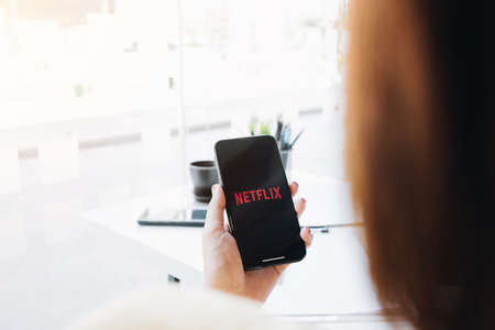 CHIANG MAI, THAILAND, MAR 12 2020: Woman hand holding Smart Phone with Netflix logo on Apple iPhone...