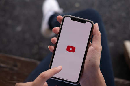 CHIANG MAI, THAILAND - NOV.17 ,2019: Woman holding iPhone Xs with Youtube apps on screen. YouTube is the popular online video sharing website.のeditorial素材