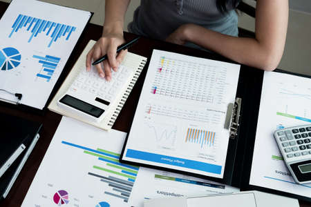Business woman using calculator and laptop for do math finance on wooden desk in office and business...
