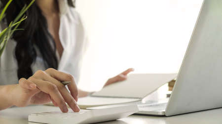 Close up of busineswosman or accountant hand holding pen working on calculator to calculate business...