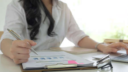 Close up of woman or accountant hand holding pen working on laptop computer for calculate business...