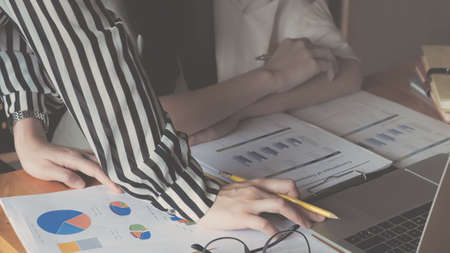 Businesswoman holding pens and holding graph paper are meeting to plan sales to meet targets set in...