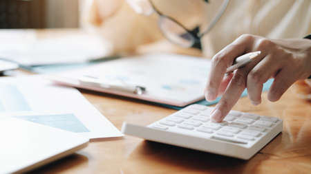 Close up Businesswoman using calculator and laptop for do math finance on wooden desk in office and...