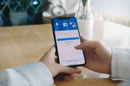 CHIANG MAI ,THAILAND JUL 25 2020 : Woman holding a iPhone X with social Internet service Facebook on the screen.のeditorial素材