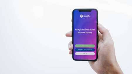 CHIANG MAI, THAILAND - JUL 17 2020: Person holding a brand new Apple iPhone XS with Spotify logo on the screen. Spotify is a popular commercial music streaming service.のeditorial素材