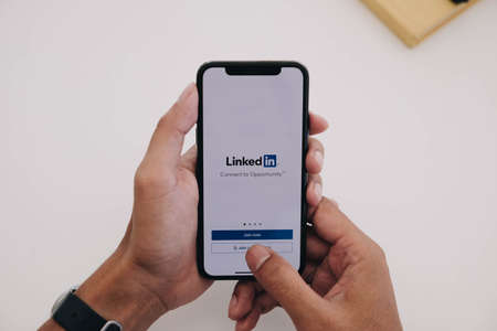 CHIANG MAI ,THAILAND MAY 21 2020 : Woman holding a iPhone Xs with social network service LinkedIn on the screen. iPhone Xs was created and developed by the Apple inc.のeditorial素材