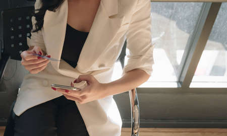Close up hand of woman holding credit card and using smartphone at office.の写真素材