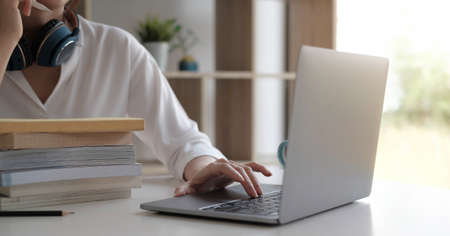 Front view on young caucasian woman study in front of the laptop computer at home - Girl reading book preparing exam test having online consultationの写真素材