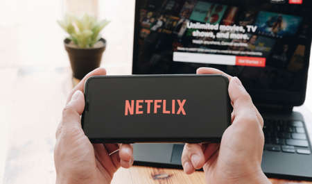 CHIANG MAI, THAILAND, MAR 21, 2021: Woman hand holding Smart Phone with Netflix logo on Apple iPhone Xs. Netflix is a global provider of streaming movies and TV series.のeditorial素材