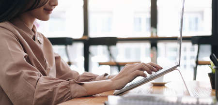 young woman pondering ideas, sitting at desk with laptop, distracted from work, beautiful female looking in distance, taking break.の写真素材