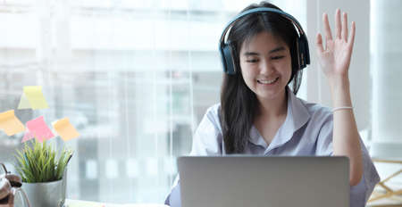 Young girl showed hands successful to her friends on a video call on laptop in the home. Sheâs happiness to learning lessons online.  Education from home.の写真素材