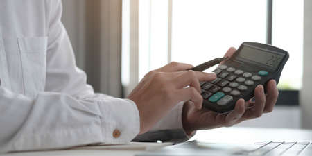 Close up Business woman using calculator and laptop for do math finance on wooden desk in office and...