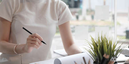 Closeup asian woman writing on notebook on table with laptop, girl work at coffee shop, freelance business concept.の写真素材
