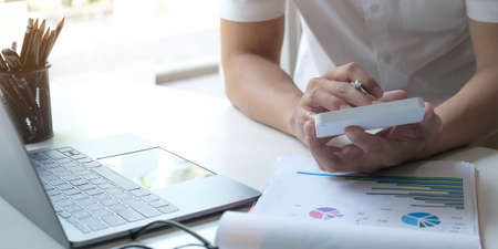 Close up Businessman using calculator and laptop for do math finance on wooden desk in office and...