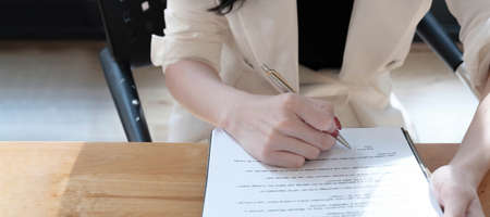 real estate agent assisting client to sign contract paper at desk with house model