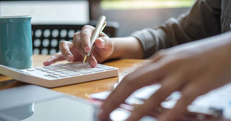 Close up Hands of businesswoman or accountant holding pen and working on calculator to calculate...