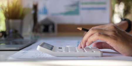 Close-up Of A Businessman Calculating Invoice Using Calculator At Workplaceの写真素材