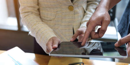 businessmen and woman sitting, using laptop computer and discussing questions at meeting in sunny...