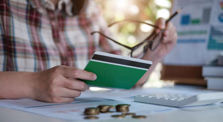 Young Asian woman checking bills, taxes, bank account balance and calculating credit card expenses....