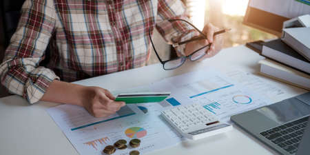 Young Asian woman checking bills, taxes, bank account balance and calculating credit card expenses....