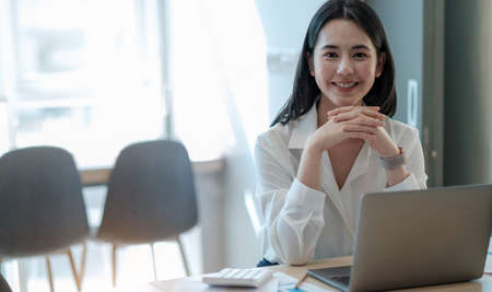 Beautiful young Asian girl working at a office space with a laptop.の写真素材