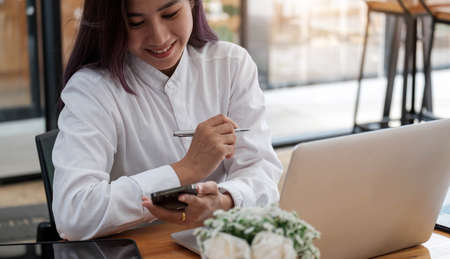 Portrait of attractive asian business woman working with smartphone for group online meeting conference,の写真素材
